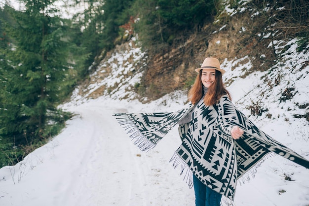 Retrato al aire libre de una mujer joven rodeada de bosques cubiertos de nieve y el concepto de turismo de montaña