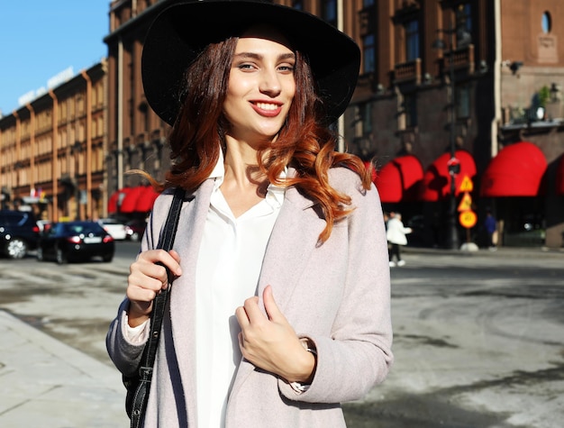 Retrato al aire libre de yong hermosa mujer sonriente feliz con elegante abrigo de sombrero