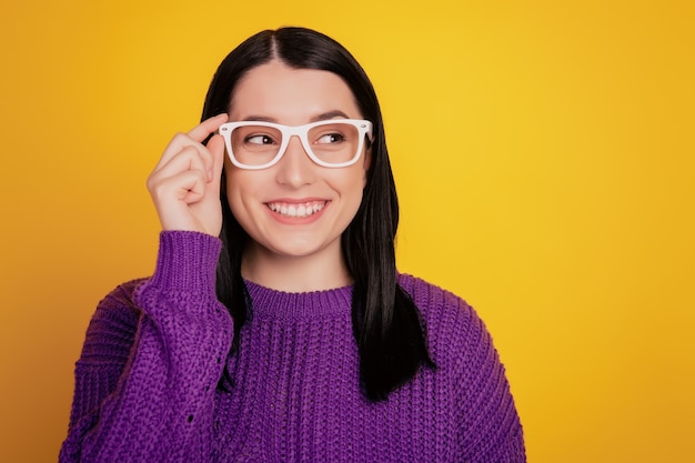 Retrato de alegre agradable elegante lindo joven inteligente gafas de tacto de la mano mirar el espacio vacío aislado sobre fondo de color amarillo