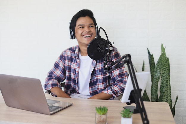 Retrato de un alegre y atractivo presentador de radio asiático hablando durante el podcast