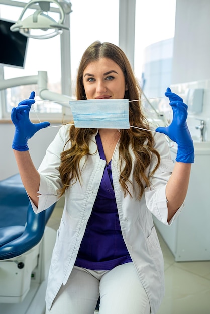 Retrato de una alegre dentista uniformada mirando a la cámara solo en la atención médica de la clínica moderna