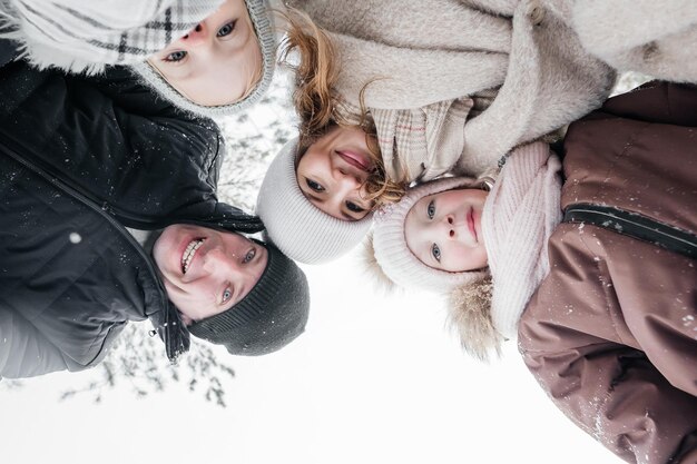 Foto retrato alegre de la familia tomado desde abajo en el bosque de invierno