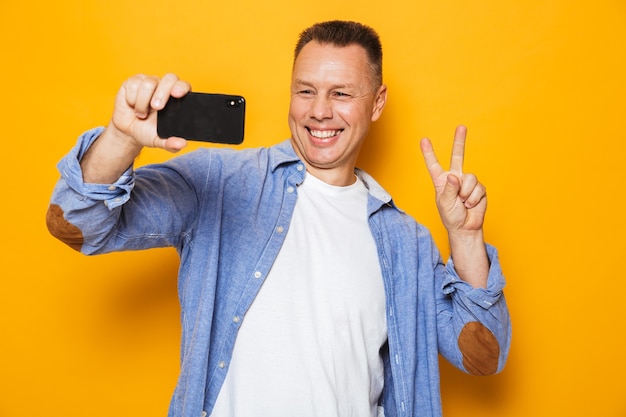 Retrato de un alegre hombre de mediana edad tomando un selfie