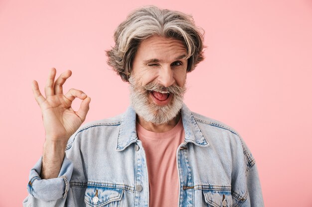 Retrato de un alegre hombre de mediana edad vestido con traje casual que se encuentran aisladas, mostrando gesto ok