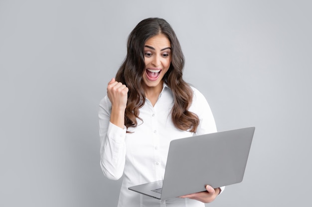 Retrato alegre jovem casual em pé isolado sobre fundo cinza usando computador portátil