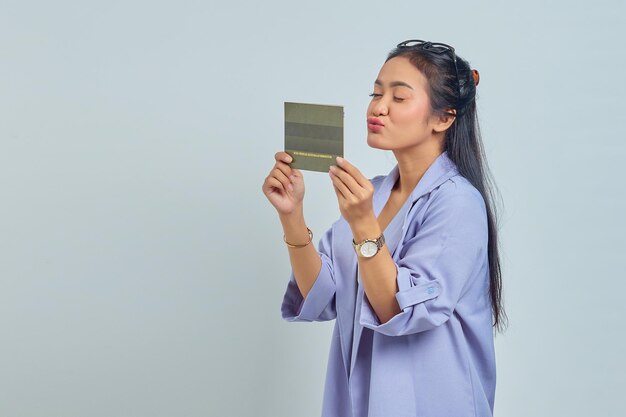 Retrato de una alegre joven asiática sosteniendo las palmas enviando un beso de aire al libro del vehículo aislado de fondo blanco