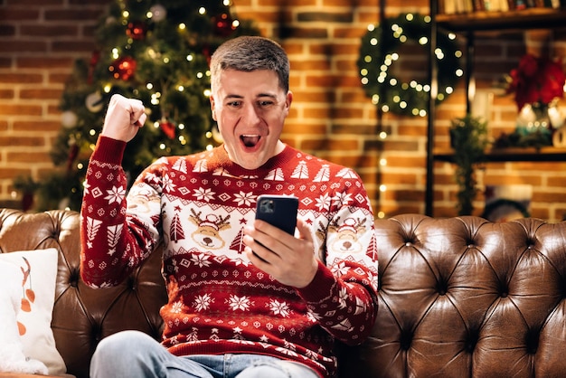 Retrato de alegre joven caucásico feliz sonriendo con cara de sorpresa tocando en el teléfono celular