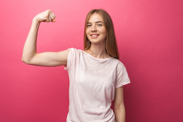 Retrato de alegre joven doblar bíceps aislado en pared rosa