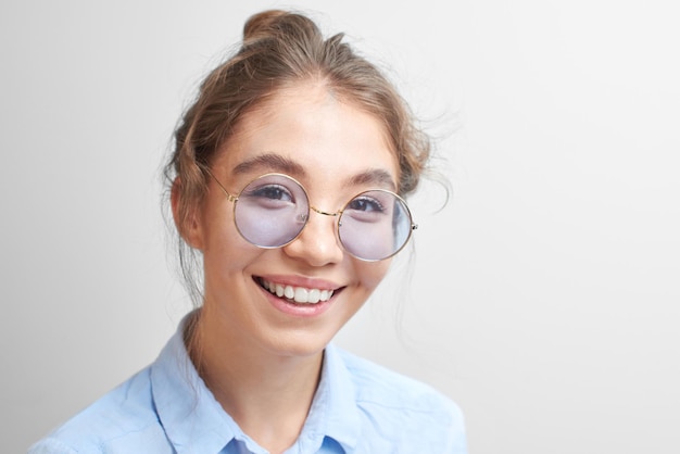 Retrato de una alegre joven kazaja asiática con gafas elegantes vestida de forma informal sonriendo alegremente aislada en un fondo blanco