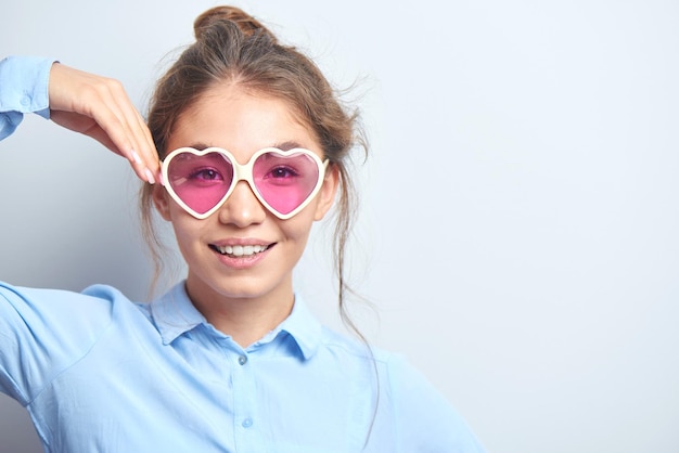 Retrato de una alegre joven kazaja asiática con gafas elegantes vestida de forma informal sonriendo alegremente aislada en un fondo blanco