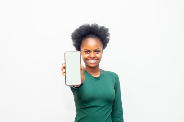 Retrato de una alegre mujer de negocios africana que muestra un teléfono móvil con pantalla en blanco aislado sobre fondo blanco