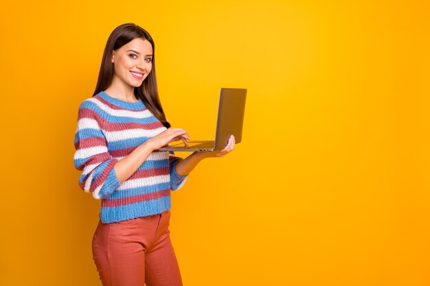 Retrato de alegre niña confiada sosteniendo en manos portátil