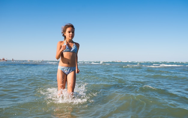 Retrato de una alegre niña positiva nadando en el mar en un soleado día de verano. El concepto de niños felices que descansan en el mar. Espacio publicitario