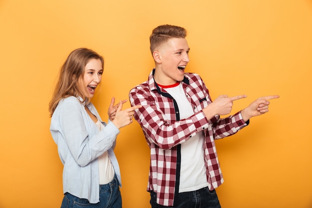 Retrato, de, un, alegre, pareja adolescente, señalar con el dedo, lejos