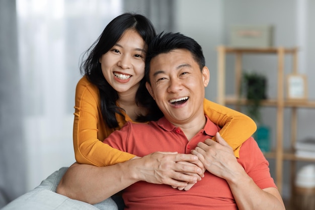 Retrato de una alegre pareja asiática posando en casa