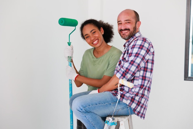 Retrato Alegre pareja joven y mujer negra sonriendo durante la renovación en un nuevo apartamento