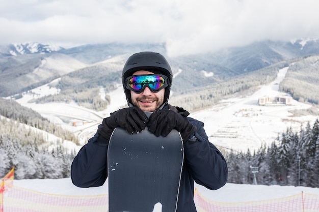 Retrato de alegre snowboarder en la parte superior de la pista de esquí en la estación de esquí