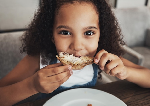 Foto retrato de almuerzo y niño comiendo pollo en el comedor en una cena de fiesta o evento en casa niña feliz y hambrienta disfrutando de comida o comida en la mesa para el hambre de bocadillos o el antojo en una casa