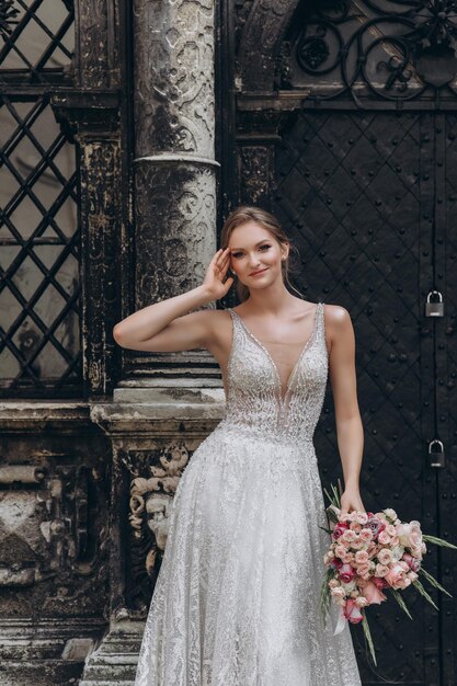 Retrato de alta moda de una joven mujer elegante al aire libre Novia con vestido blanco cerca de un edificio antiguo