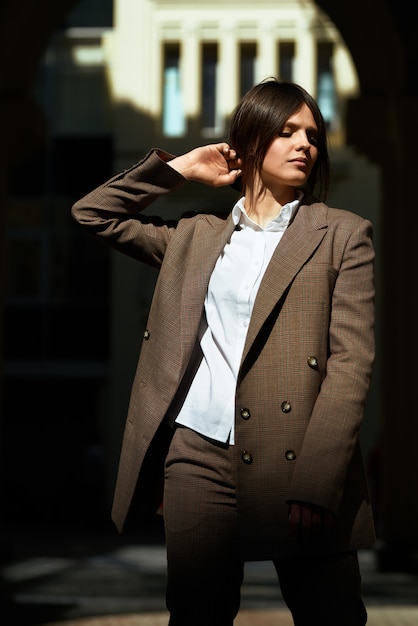 Retrato de alta moda de mujer elegante joven en traje marrón a pie en la calle. disfruta las luces de verano. Foto de moda