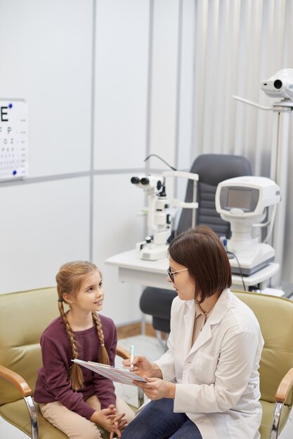 Retrato de alto ángulo de linda adolescente buscando doctora durante la consulta en la clínica moderna