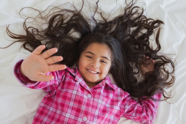 Retrato de alto ángulo de niña sonriente tumbado en la cama