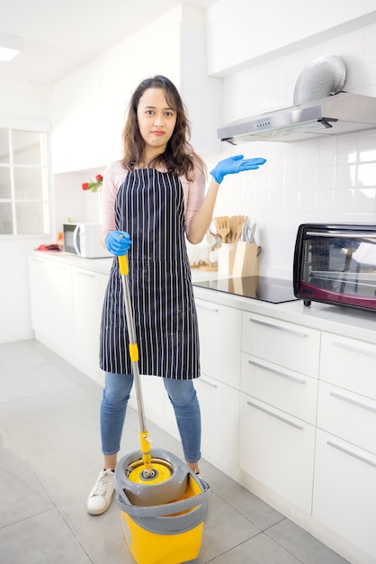 Retrato de ama de casa joven alegre sosteniendo suministros de limpieza