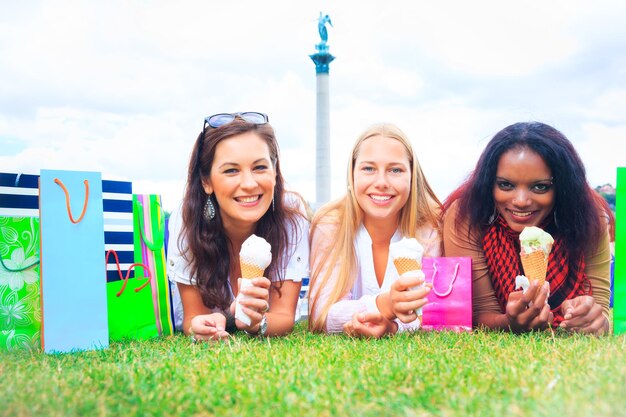 Foto retrato de amigas felices sosteniendo conos de helado mientras se relajan en el campo