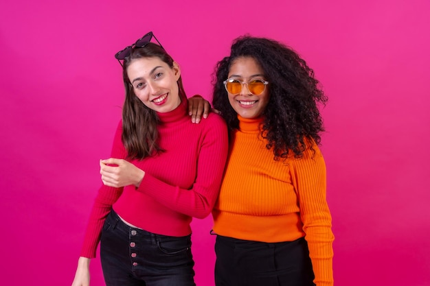 Retrato amigas en gafas de sol divirtiéndose en un estilo de vida de estudio de fondo rosa