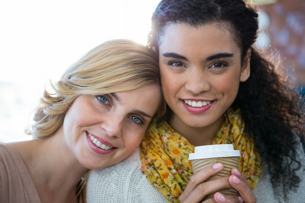 Retrato de amigas sentadas juntas y tomando un café