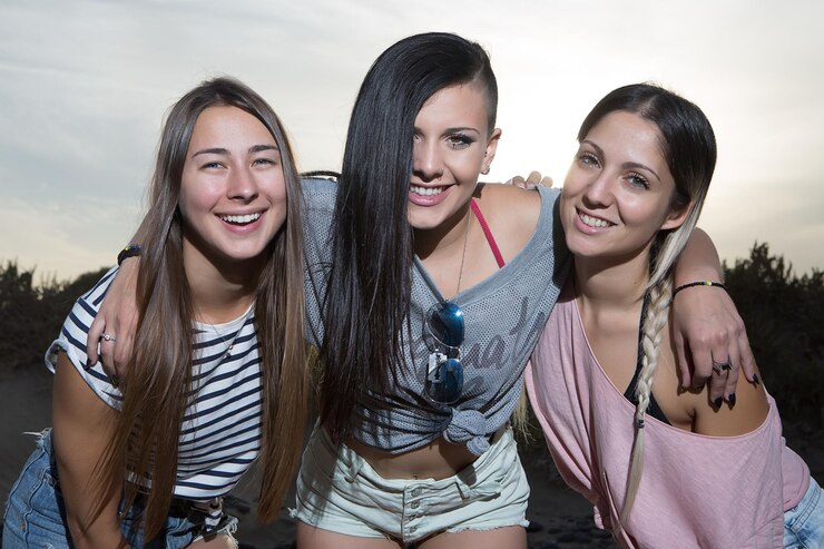 Foto retrato de amigas sonrientes contra el cielo durante la puesta de sol