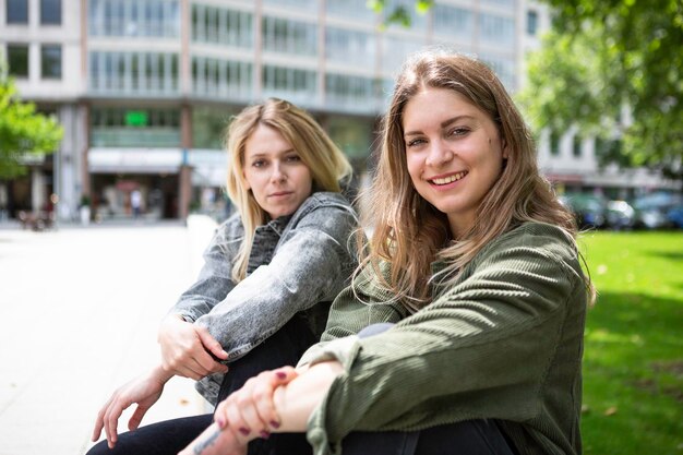 Retrato de amigas sonrientes sentadas al aire libre en la ciudad