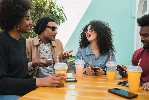 Retrato de amigos afro divirtiéndose juntos y disfrutando de un buen rato mientras beben jugo de fruta fresca.