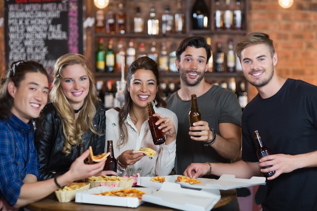 Retrato de amigos comiendo pizza con cerveza