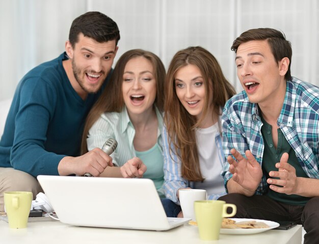 Retrato de amigos felices y portátil en casa