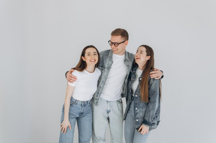 Retrato de amigos felices sobre fondo gris Dos mujeres y hombres abrazándose y sonriendo