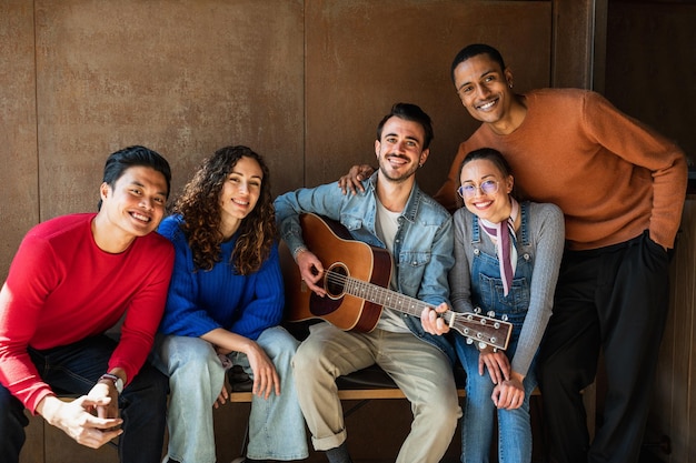 Retrato de amigos de grupo multirracial Personas mirando a la cámara con una sonrisa uno está tocando la guitarra