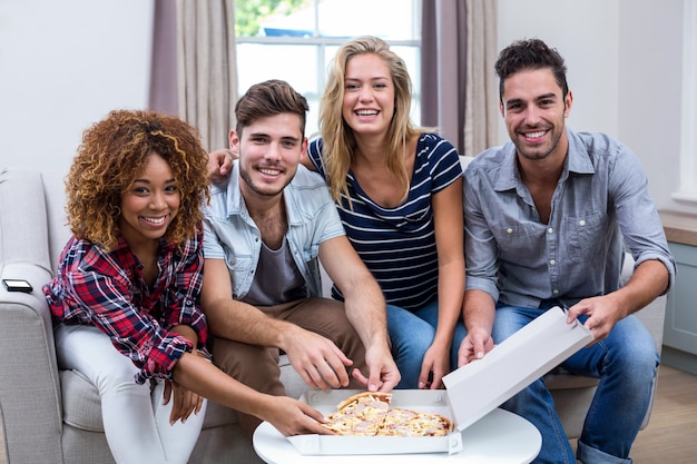 Retrato de amigos multiétnicos disfrutando de pizza en casa