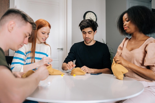 Retrato de amigos multiétnicos relajados jugando juegos de mesa sentados a la mesa en la sala de estar Gente multirracial juguetona disfrutando de la actividad de ocio