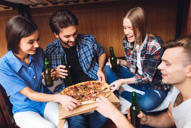 Foto retrato de amigos que se relajan juntos, comen pizza