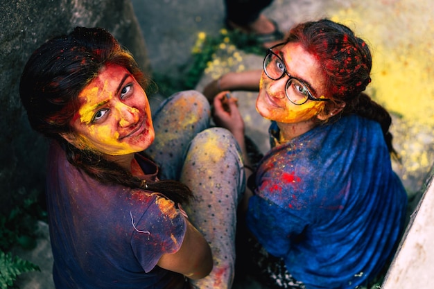 Foto retrato de amigos sonrientes cubiertos de pintura en polvo sentados al aire libre