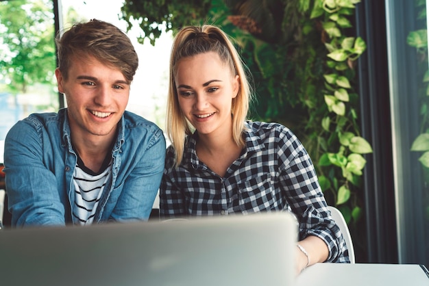 Retrato de amigos sonrientes usando una computadora portátil en casa