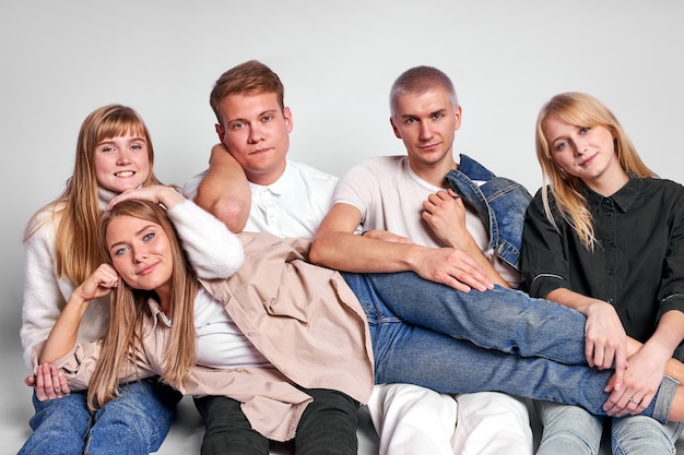 Retrato de amistosos chicos y damas caucásicos sentados en el suelo en el estudio