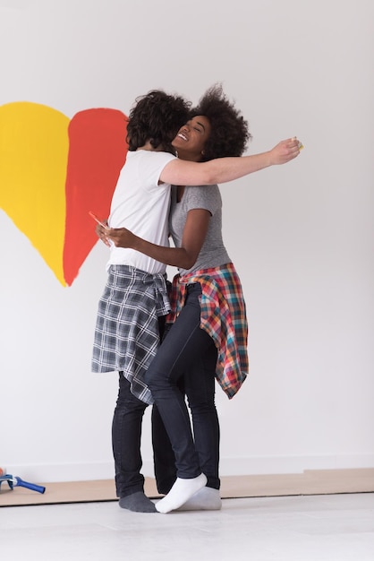 Retrato de amorosa pareja multiétnica con corazón pintado en la pared