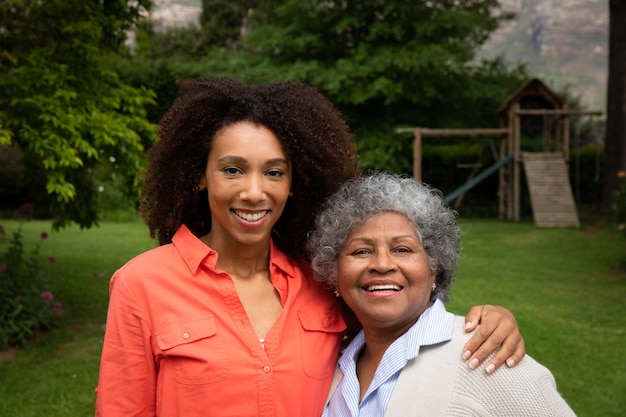 Retrato de una anciana afroamericana con su hija en el jardín, sonriendo a la cámara y abrazándose. Familia disfrutando del tiempo en casa, concepto de estilo de vida