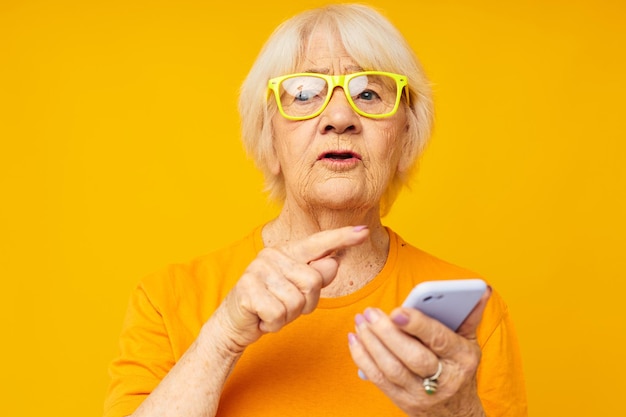Retrato de una anciana amigable estilo de vida feliz en camisetas amarillas con fondo de teléfono aislado