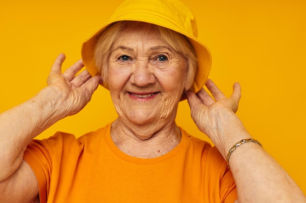 Retrato de una anciana amigable estilo de vida feliz en un tocado amarillo fondo amarillo