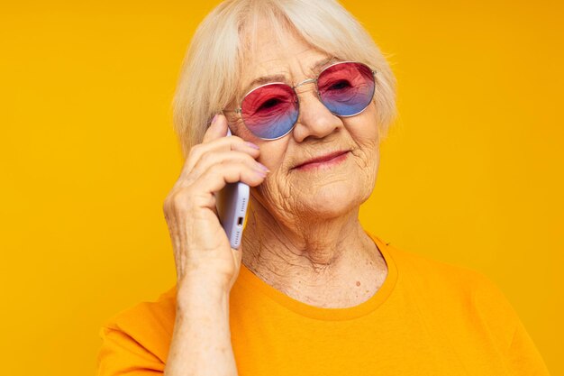 Retrato de una anciana amigable con gafas de moda con un fondo aislado de teléfono inteligente