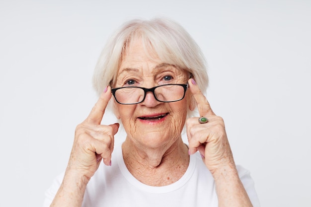 Retrato de una anciana amigable con problemas de visión con anteojos de fondo claro