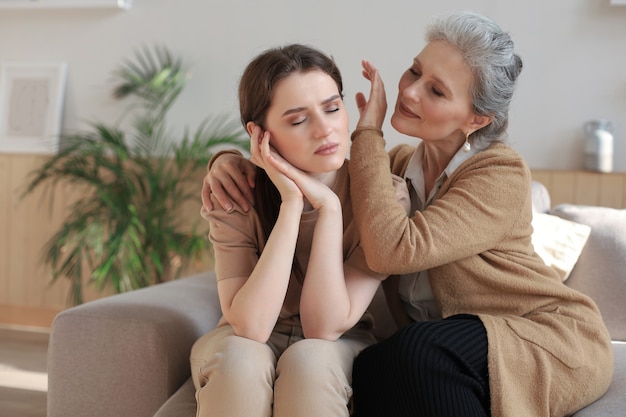 Retrato de anciana e hija madura abrazándose en casa. Felices relaciones de confianza. Concepto de familia.